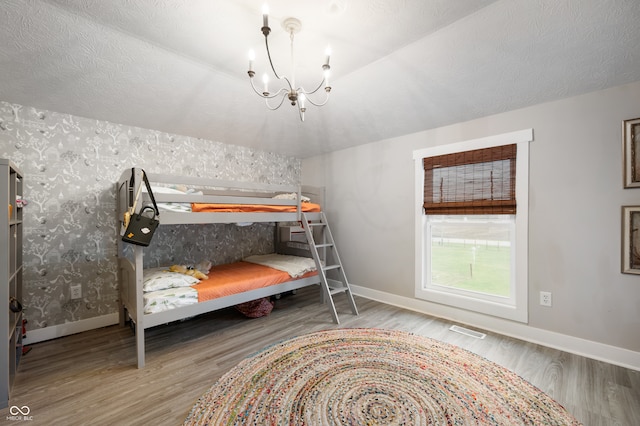 unfurnished bedroom with vaulted ceiling, an inviting chandelier, and hardwood / wood-style flooring