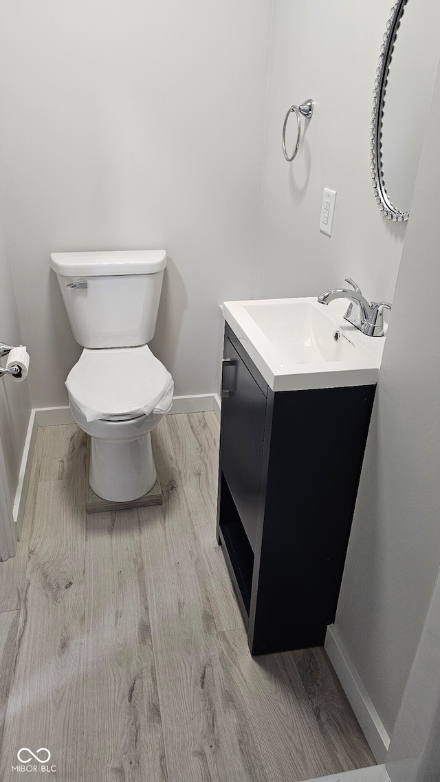 bathroom with hardwood / wood-style floors, vanity, and toilet