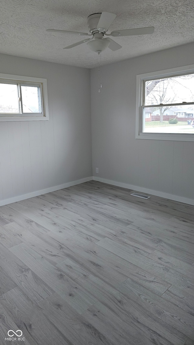 spare room featuring ceiling fan, a textured ceiling, and light wood-type flooring