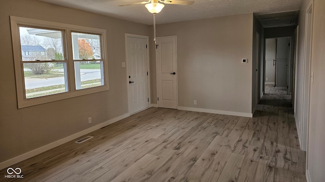 spare room with a textured ceiling, light wood-type flooring, and ceiling fan