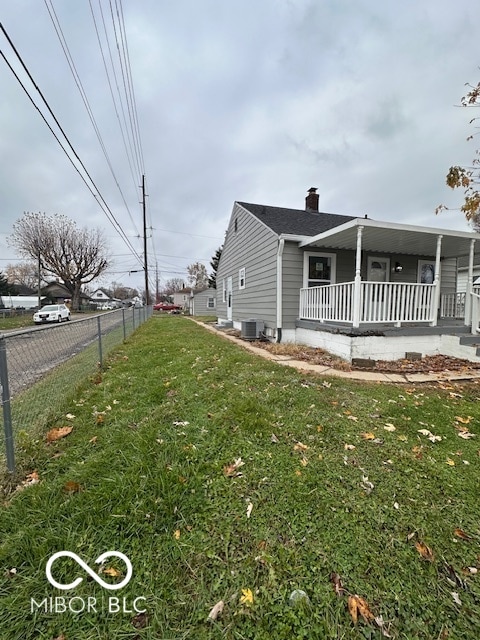 view of side of home with a porch, a yard, and central air condition unit