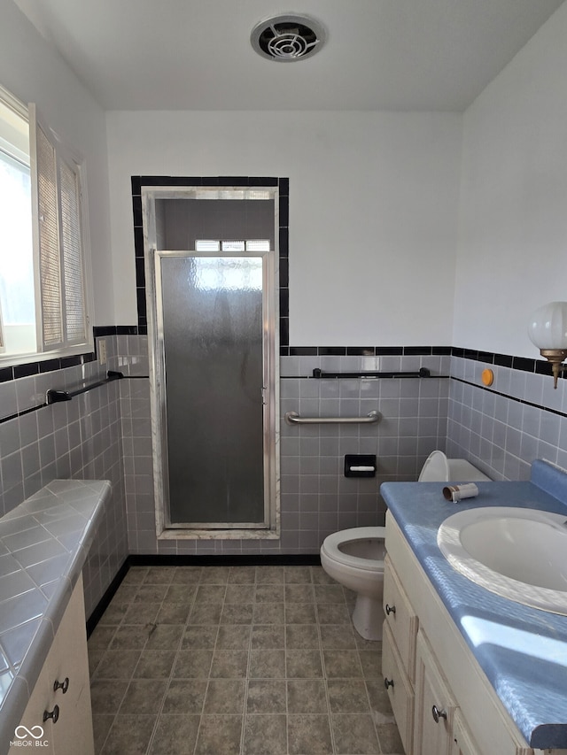 bathroom featuring vanity, tile patterned floors, an enclosed shower, and tile walls