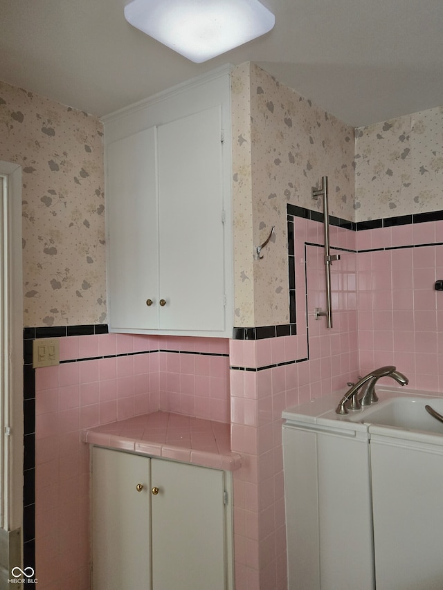 bathroom featuring a washtub, tile walls, and sink