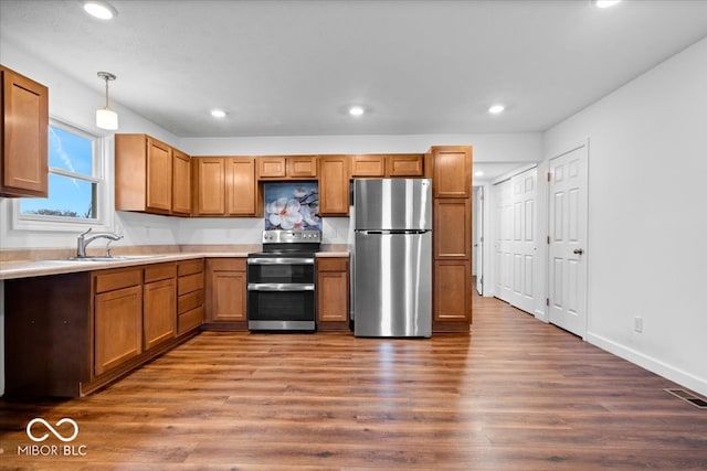 kitchen with dark hardwood / wood-style floors, sink, stainless steel appliances, and hanging light fixtures