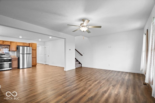 unfurnished living room featuring a textured ceiling, ceiling fan, and dark wood-type flooring