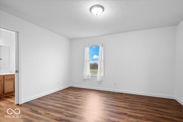 unfurnished room with dark hardwood / wood-style flooring and a textured ceiling