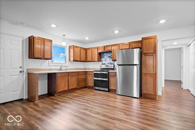 kitchen featuring sink, dark hardwood / wood-style flooring, hanging light fixtures, and appliances with stainless steel finishes