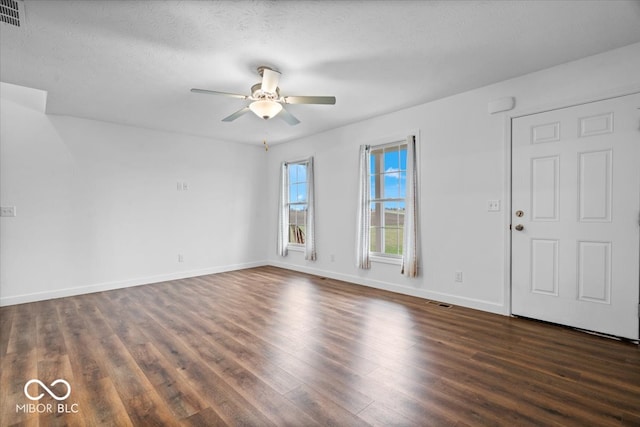 spare room featuring ceiling fan, dark wood-type flooring, and a textured ceiling