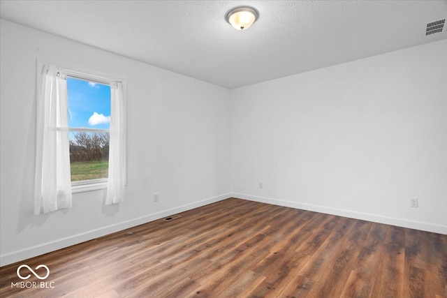 empty room featuring a textured ceiling and dark hardwood / wood-style flooring