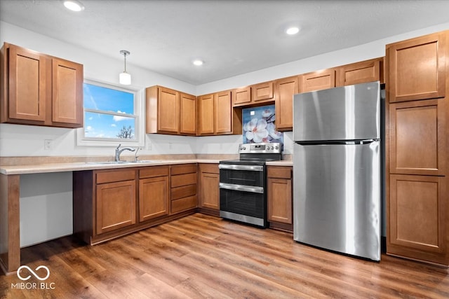 kitchen featuring wood-type flooring, stainless steel appliances, decorative light fixtures, and sink