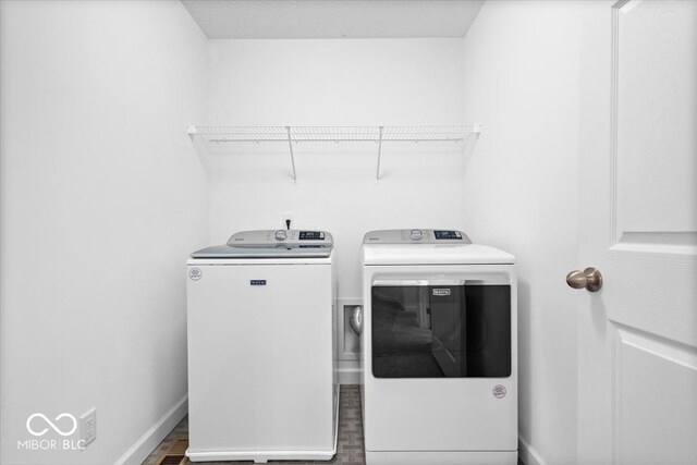 clothes washing area featuring hardwood / wood-style flooring and washing machine and clothes dryer