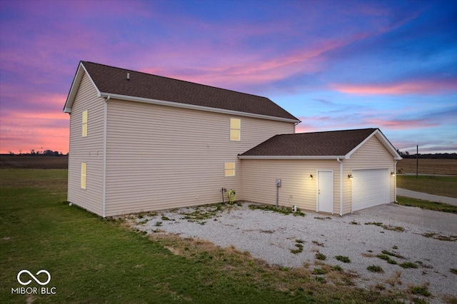 property exterior at dusk with a garage and a yard