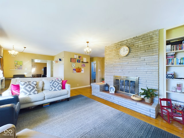 living room with a chandelier, wood-type flooring, and a brick fireplace