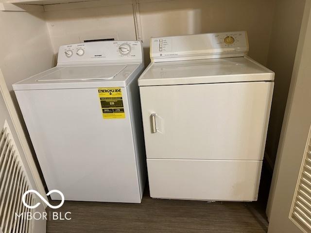 clothes washing area featuring dark wood-type flooring and washer and clothes dryer