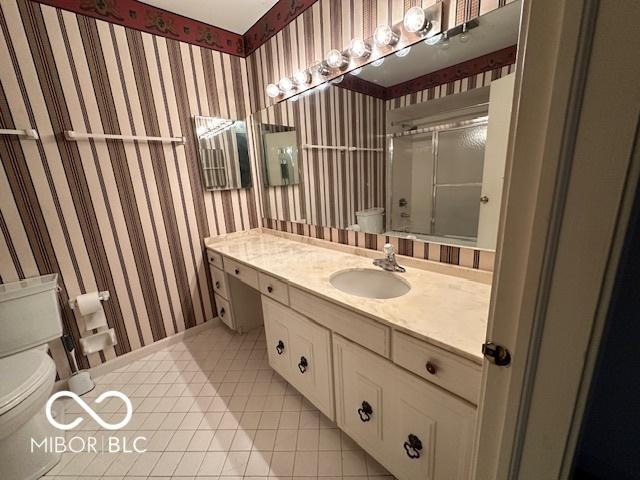 bathroom featuring tile patterned flooring, vanity, a shower with shower door, and toilet