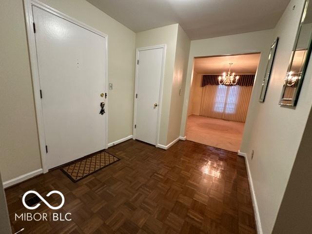 foyer entrance with a notable chandelier and dark parquet flooring