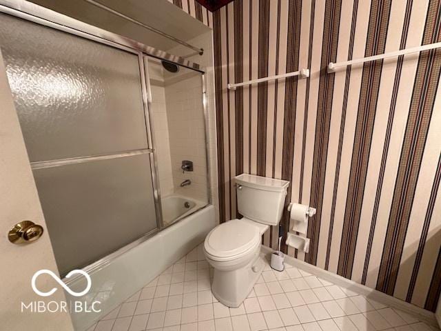 bathroom featuring bath / shower combo with glass door, tile patterned floors, and toilet