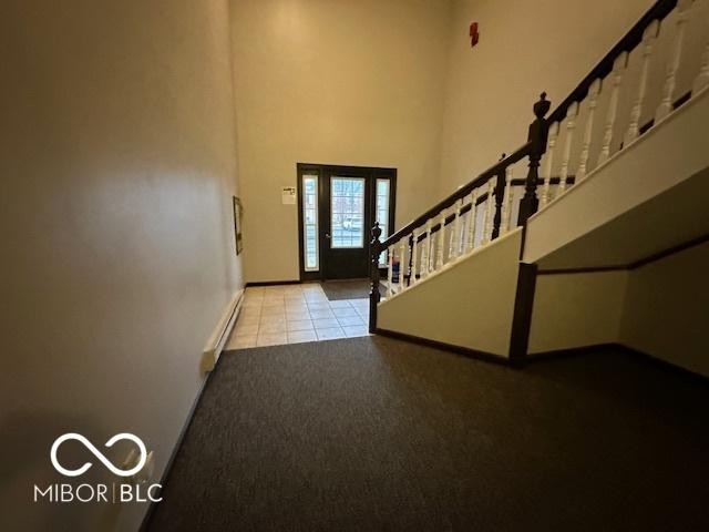 foyer featuring light tile patterned flooring, a baseboard heating unit, and a high ceiling