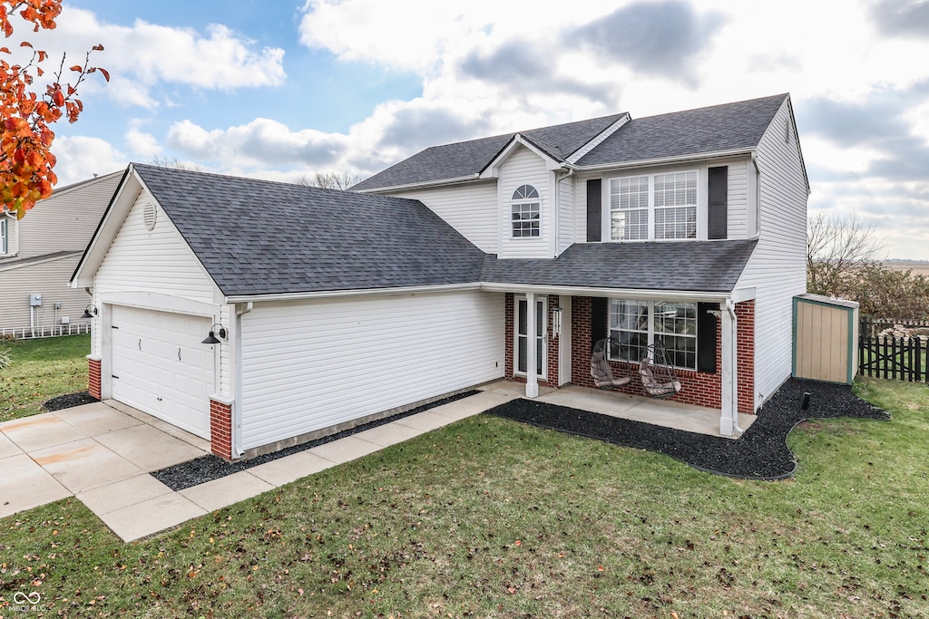 front of property with covered porch, a garage, and a front lawn