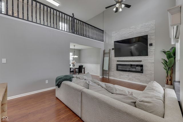 living room featuring ceiling fan with notable chandelier, hardwood / wood-style floors, and a towering ceiling