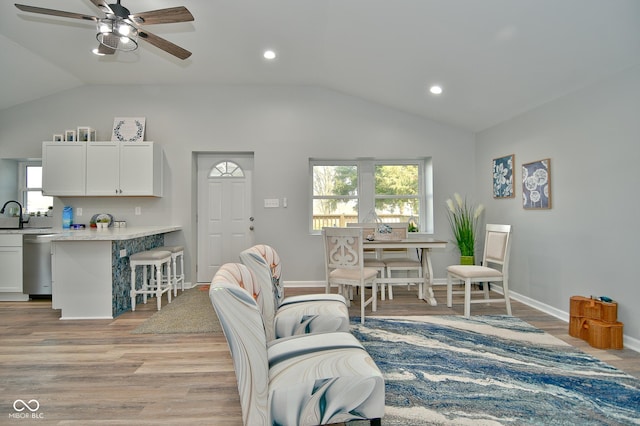 living room with ceiling fan, light hardwood / wood-style floors, lofted ceiling, and sink