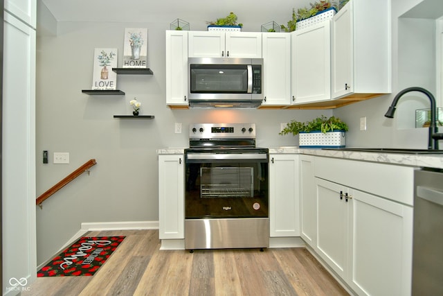 kitchen featuring stainless steel appliances, white cabinetry, light hardwood / wood-style floors, and sink