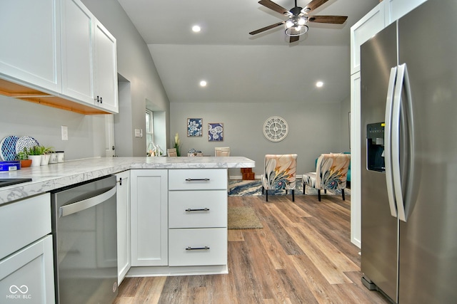 kitchen with white cabinets, appliances with stainless steel finishes, light wood-type flooring, and vaulted ceiling