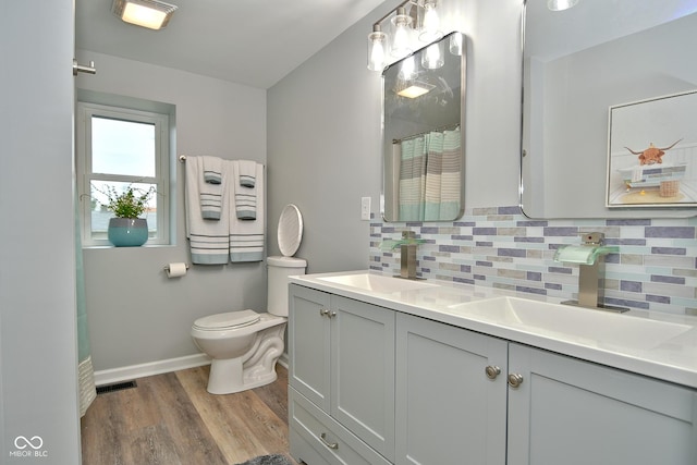 bathroom featuring vanity, toilet, wood-type flooring, and tasteful backsplash