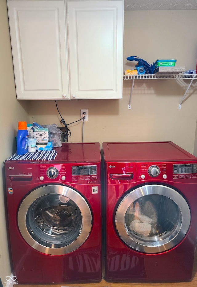 clothes washing area featuring cabinets and washing machine and clothes dryer