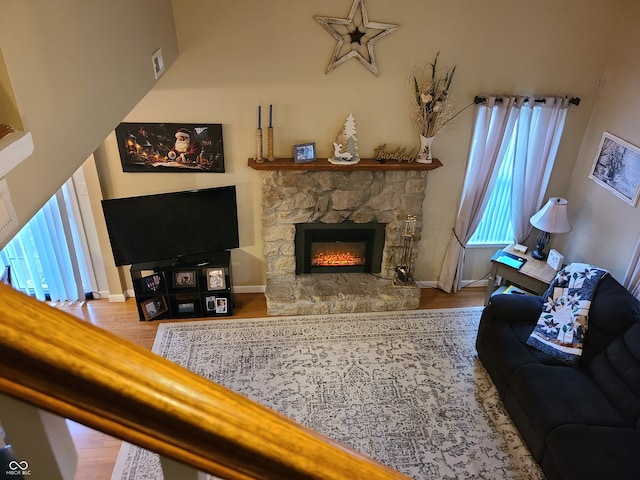 living room featuring hardwood / wood-style floors, a stone fireplace, and a high ceiling