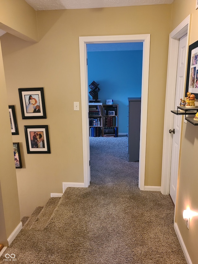 hallway featuring carpet floors and a textured ceiling