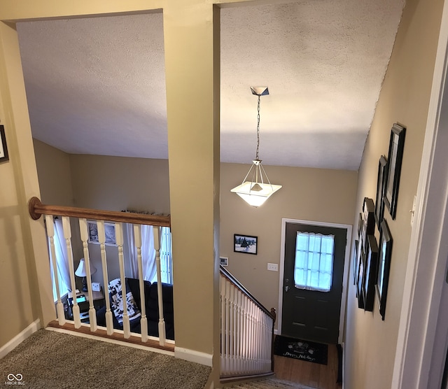 foyer entrance featuring carpet, a textured ceiling, and vaulted ceiling