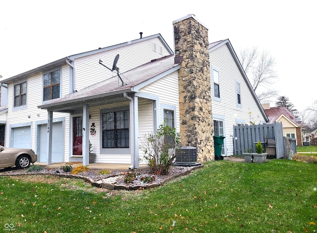 view of front of home featuring central AC unit, a front yard, and a garage