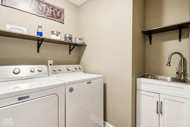 laundry room featuring cabinets, washing machine and clothes dryer, and sink