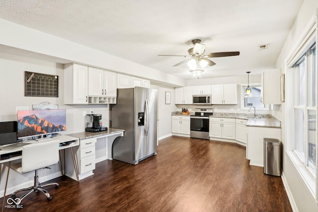 kitchen featuring dark hardwood / wood-style floors, pendant lighting, white cabinets, stainless steel appliances, and light stone countertops