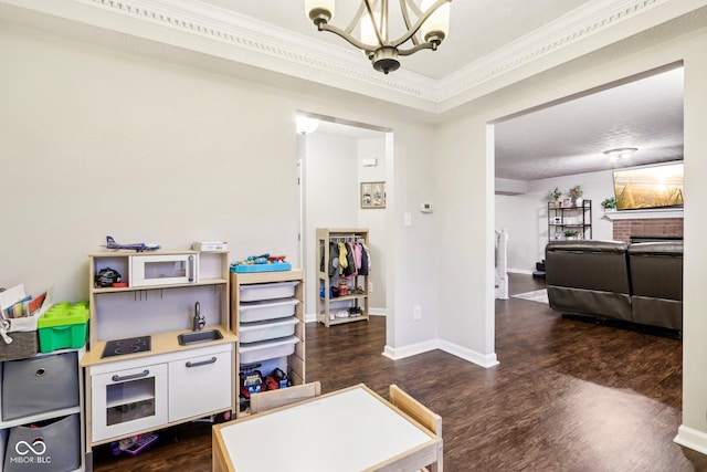 recreation room featuring an inviting chandelier, ornamental molding, and dark hardwood / wood-style floors