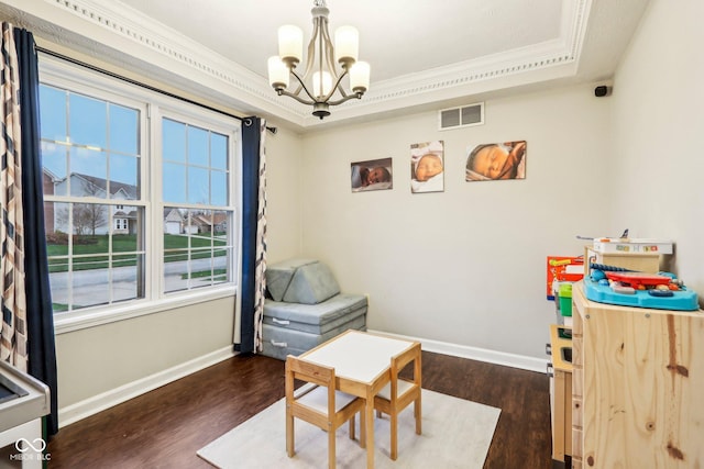 interior space featuring dark wood-type flooring, ornamental molding, a tray ceiling, and an inviting chandelier