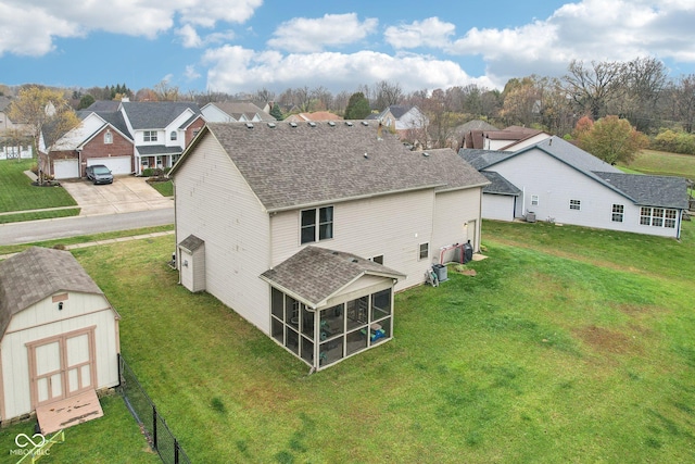 back of house featuring a sunroom, a yard, and a storage shed