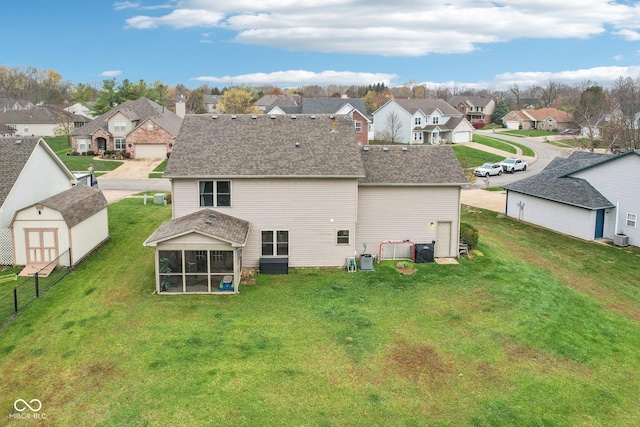 rear view of house featuring a storage shed, central AC unit, a lawn, and a sunroom