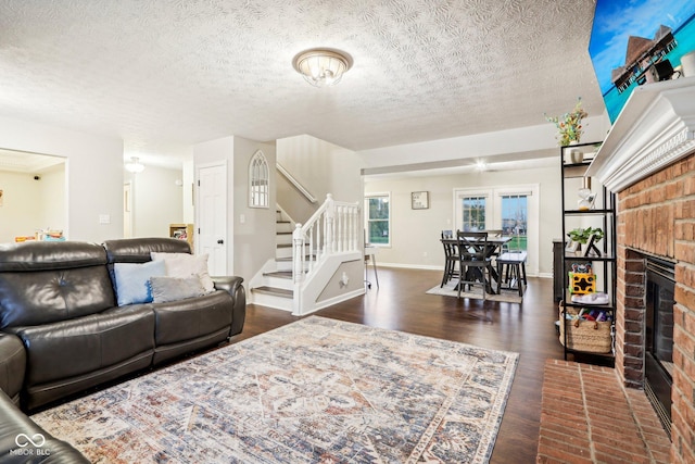 living room with dark hardwood / wood-style floors, a brick fireplace, and a textured ceiling