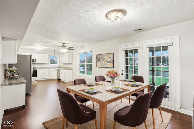 dining room with sink, dark hardwood / wood-style flooring, ceiling fan, a textured ceiling, and french doors