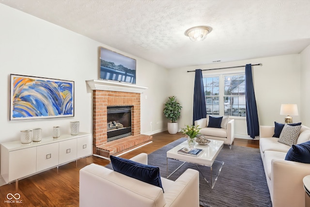 living room featuring dark wood-type flooring, a brick fireplace, and a textured ceiling