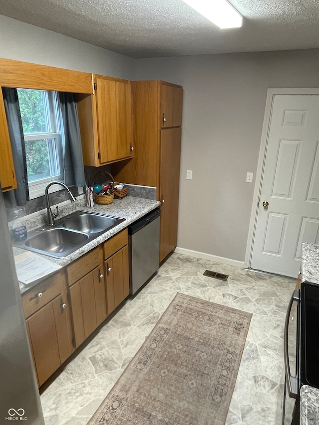 kitchen with stainless steel dishwasher, sink, and a textured ceiling