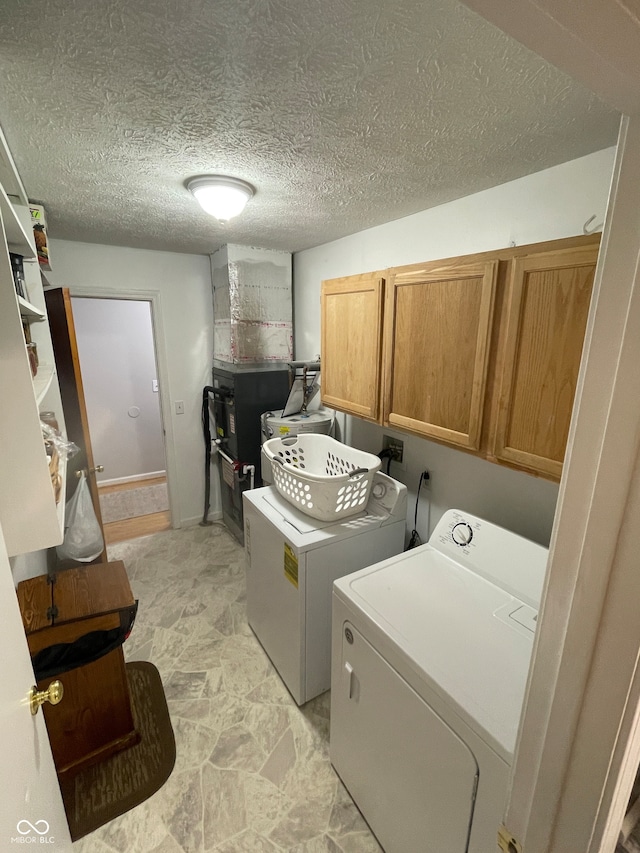 washroom with cabinets, independent washer and dryer, and a textured ceiling