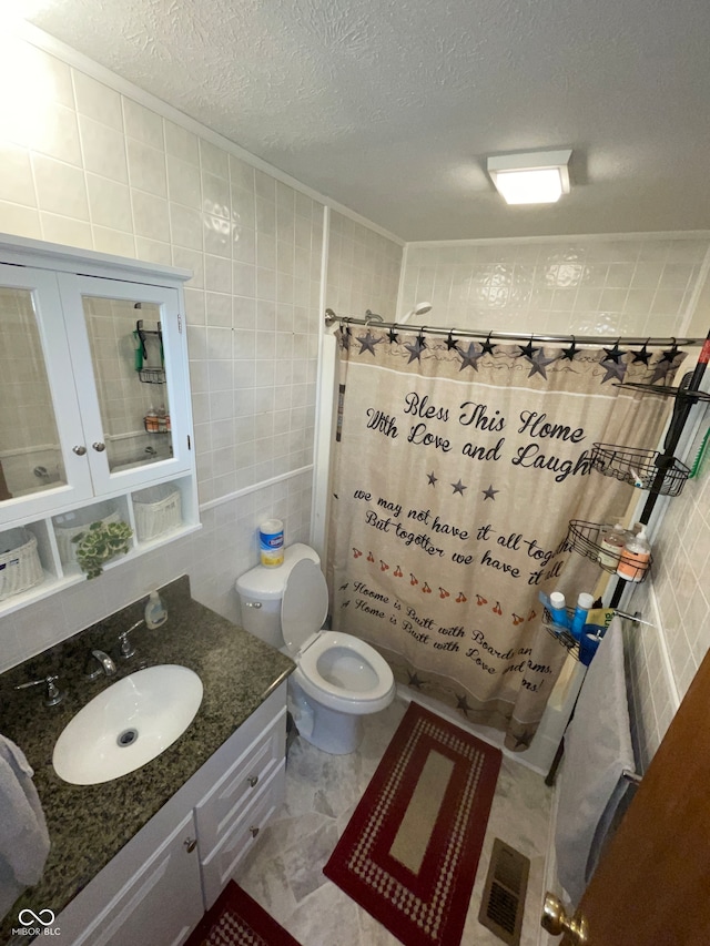 bathroom with a textured ceiling, vanity, curtained shower, and tile walls