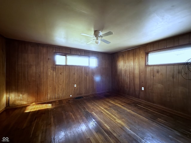 unfurnished room with ceiling fan, dark hardwood / wood-style floors, and wood walls