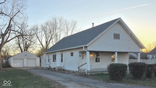 view of front of house with a porch, a garage, central air condition unit, and an outbuilding