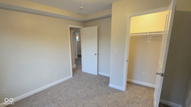 unfurnished bedroom with light colored carpet and a closet