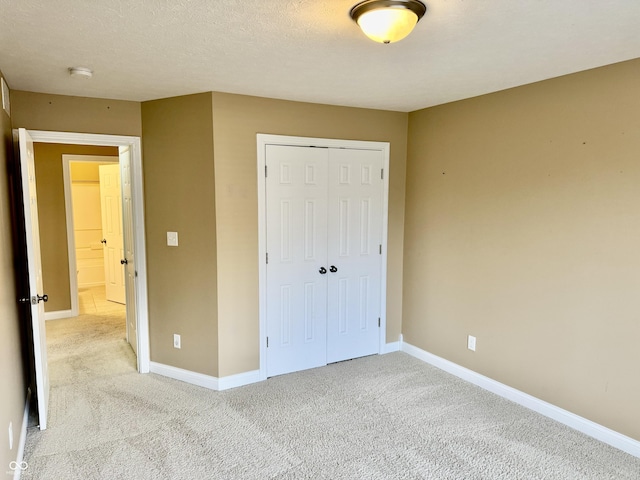 unfurnished bedroom featuring a textured ceiling, light colored carpet, and a closet