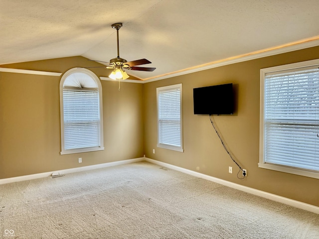 carpeted spare room with ornamental molding, lofted ceiling, ceiling fan, and a healthy amount of sunlight